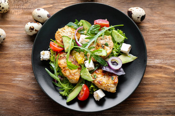 Plate with tasty chicken salad on wooden table