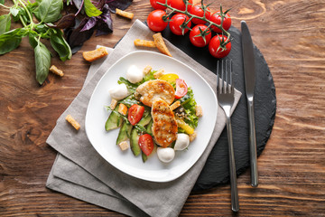Plate with tasty chicken salad on wooden table