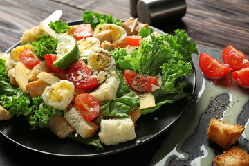 Plate with tasty Caesar salad on wooden table, closeup