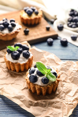 Tasty tartlets with blueberries on table
