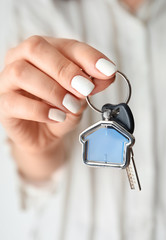 Woman holding key with trinket in shape of house, closeup