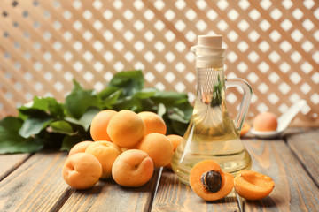 Jug of apricot essential oil on wooden table