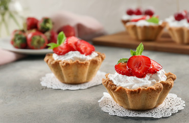 Tasty tartlets with strawberry on table