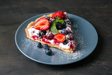 Plate with piece of delicious berry pie on table