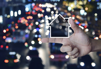 House icon with copy space on finger over blur colorful night light city with cars, Business real estate communication concept
