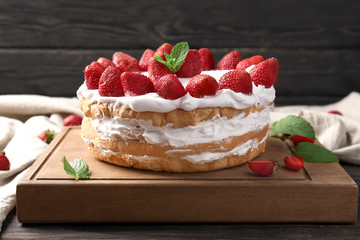 Delicious cake with strawberries on wooden board