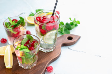 Glasses of fresh raspberry mojito on light table