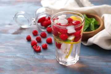 Glass of fresh raspberry mojito on wooden table