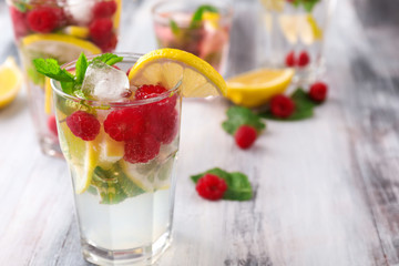 Glass of fresh raspberry mojito on wooden table