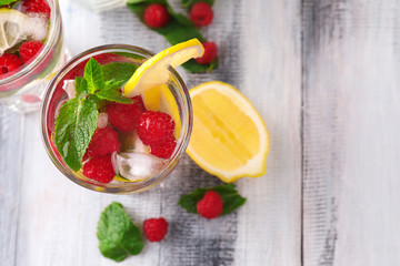 Glass of fresh raspberry mojito on wooden table