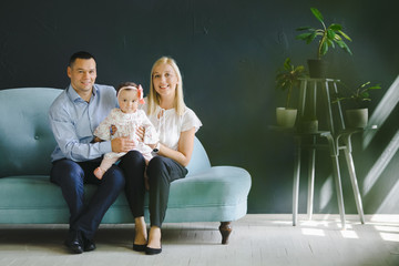 Obraz premium The mother and father embracing their daughter and sitting on the sofa