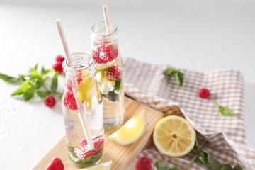 Glass bottles of fresh raspberry mojito on white table
