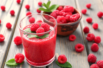 Glass of tasty raspberry smoothie on wooden table