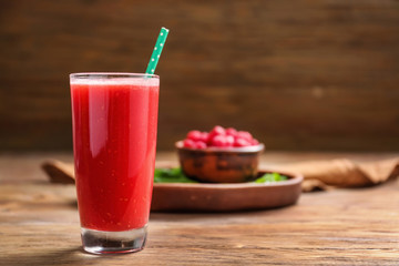 Glass of tasty raspberry smoothie on wooden table