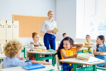 beautiful smiling teacher walking by classroom full of happy children
