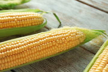 Fresh corn cobs on wooden background, closeup