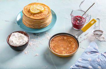 Delicious thin pancakes with jam and flour on light table