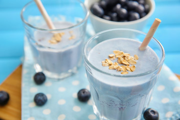 Glasses with tasty blueberry smoothie on color wooden table