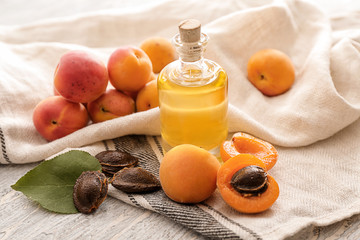 Bottle with essential oil and fresh apricots on table