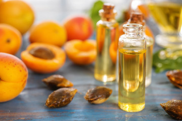 Bottles with apricot essential oil on wooden table