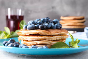 Plate with tasty pancakes and blueberries on table, closeup
