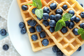 Delicious waffles with blueberries on plate, closeup