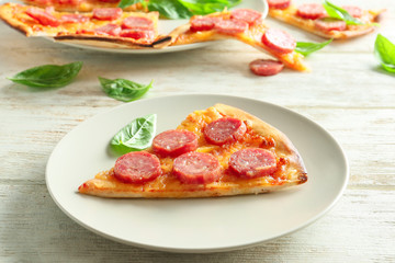 Plate with slice of tasty pizza on wooden table