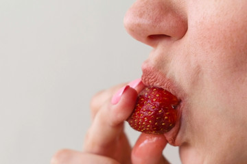 Woman eats strawberries. Mouth close-up. Side view.