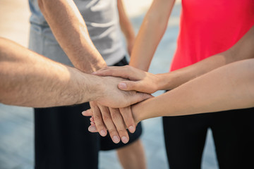 Group of sporty people putting hands together outdoors, closeup