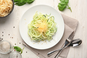 Plate of spaghetti with zucchini and cheese on table