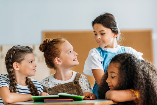 schoolgirls chatting with their classmate during break at classroom