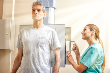 Man undergoing scan test with the help of female doctor, sun rays coming from outdoor