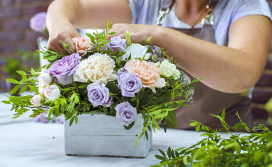 timelapse professional florist arranging flower composition in wooden box in floral design studio. Caucasian female master in apron creating floral design. Floristry, handmade, small business concept - obrazy, fototapety, plakaty