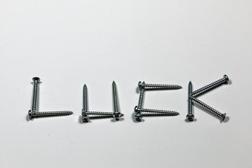 The word luck written with screws on a white background with reflections