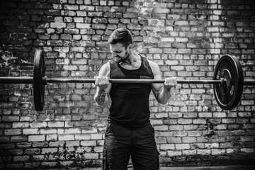 Muscular fitness man doing deadlift a barbell over his head in outdoor, street gym. Functional...
