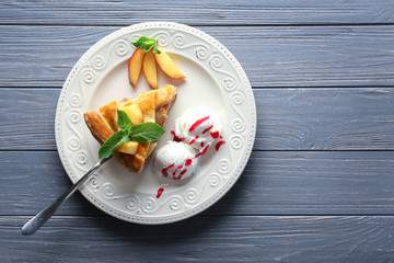 Plate with piece of tasty homemade peach pie and ice-cream on wooden table