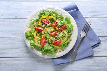 Plate with healthy fresh salad on wooden table