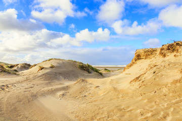 Newly formed Dunes on Dutch North Sea coast at IJmuiderslag with wind sweeping stripes in the sand  against the background of blue sky with scattered clouds