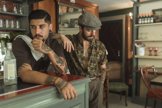 Vintage men tattooing and posing in a retro bar