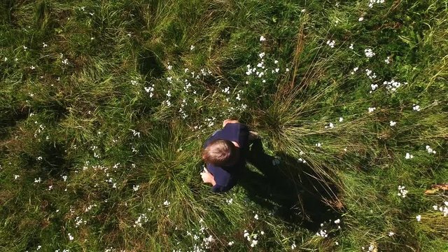 Drone flying up over a man in a field with flowers
