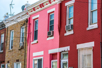 Naklejka premium Pink, red, and brown row houses in a row on a bright summer day with a blue sky in the background