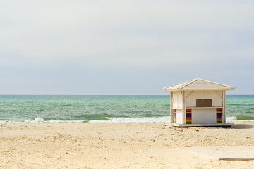 Ocean background. Empty beach. White beach huts next to the sea.