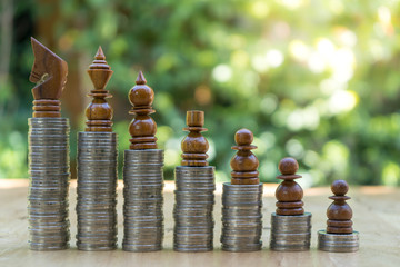 Close-up Of Chess Pieces On Stacked Coins Against green Background