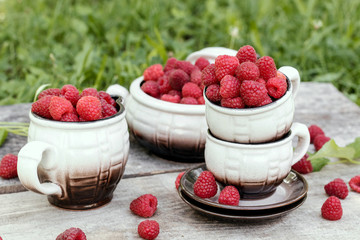 Summer still life, cups full of ripe raspberries. Summer in village.