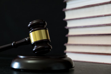 Judge gavel beside pile of books on wooden background