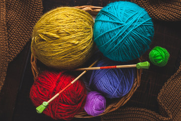 Knitting needles, bright yarn for knitting, knitted, brown scarf on a dark background. Top view