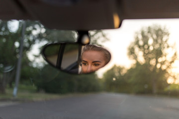 Frau fährt Auto und blickt in den Rückspiegel