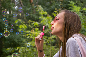 Girl blowing a soap bubbles outdoor. Happy summer holidays.