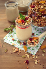Yogurt topped with granola and mint in a glass jar 