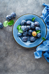 Fresh juicy sweet plums on plate with leaves